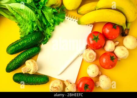 Open recipe book with set of raw organic vegetables on yellow background, copy spae for text Stock Photo