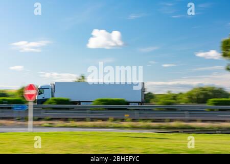 Truck with refrigerated semi-trailer driving on the highway with a blue sky with some clouds Stock Photo
