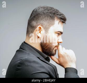 Young handsome man with beard and hand on chin thinking about question, pensive expression. thoughtful face. Doubt concept. Stock Photo