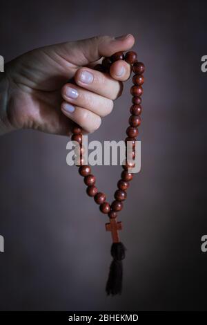 womans hand with wooden rosary or prayer beads Stock Photo