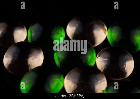 green and pink colored glass spheres on a black reflective background create an abstract design. The translucent balls appear to glow. Copy space Stock Photo