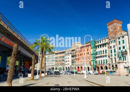 Genoa, Italy, September 11, 2018: Row of colorful buildings, palms, overpass, Tower Torre dei Morchi on Piazza Caricamento square near harbor in historical centre of old european city Genova, Liguria Stock Photo