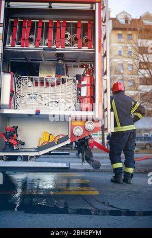 Fire truck with fire fighting equipment.Man firefighter in uniform near fire engine. Stock Photo