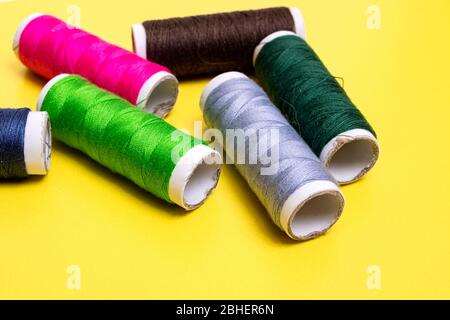 Coils with multicolored threads on yellow background Stock Photo