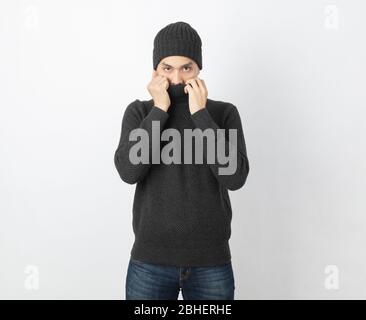 Young handsome asian man wearing grey sweater and beanie trembling, shaking from cold wind, freezing on white background. Stock Photo