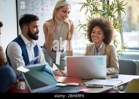 smiling business colleagues looking  content on a monitor  in modern open space office. casual modern business Stock Photo
