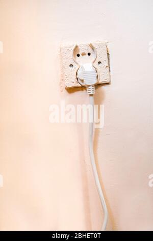 Old electrical socket with power cable pluged in Stock Photo