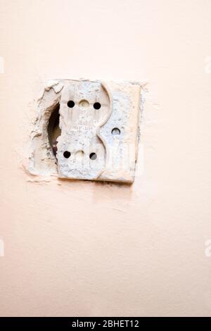 Old and broken electrical socket on the wall Stock Photo