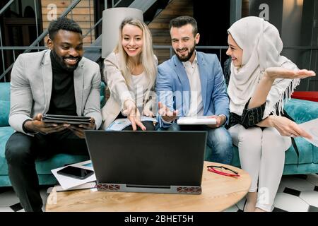 Business team success achievement concept. Happy multinational young managers successfuly completed their joint business project and looking at Stock Photo
