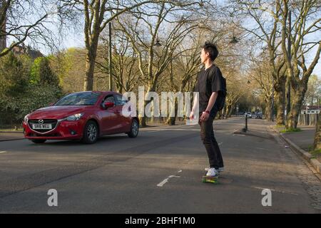 Glasgow, UK. 25th Apr, 2020. Pictured: A skate boarder travels down the road beside the park. Scenes from the first weekend of the extended lockdown from KelvinGrove Park in Glasgow's West End during a very hot and sunny Saturday. Credit: Colin Fisher/Alamy Live News Stock Photo