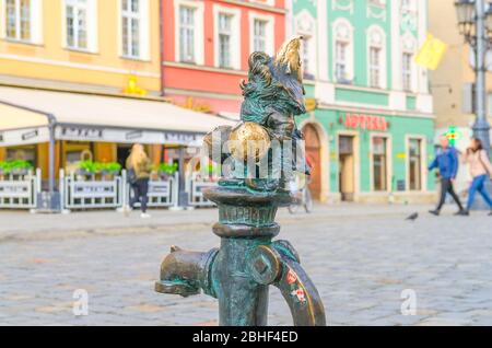 Wroclaw, Poland, May 7, 2019: Dwarf is sitting on street water tap on Rynek Market Square, famous bronze miniature gnome with hat sculpture is a symbol of Wroclaw in old historical city centre Stock Photo