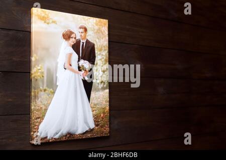 Photo canvas print. Sample of stretched wedding photography with gallery wrap, side view. Bridal portrait hanging on brown wooden wall Stock Photo