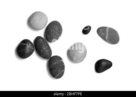Scattered sea pebbles. Smooth gray and black stones isolated on white background. Top view Stock Photo