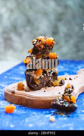 Sliced homemade chocolate with dried apricots, raisins, flax seeds, sesame seeds. on a blue background. Stock Photo