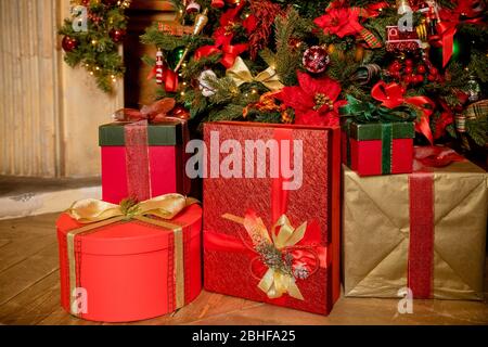 Stacks of colorful presents under a Christmas tree.Winter Holiday Concept.room interior. Christmas tree decorated with balls and bows, with gifts Stock Photo