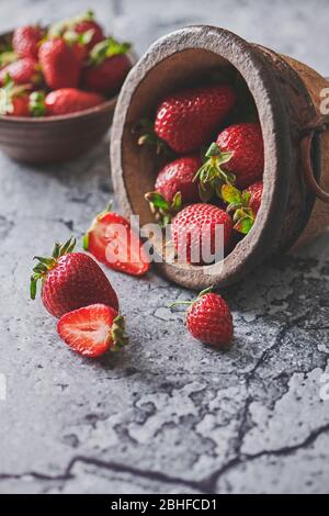 Still life with strawberries in an old ceramic bowl on a cement texture background Stock Photo