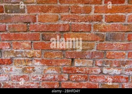 Red brick pattern. Old brick wall with cracks and scratches. Horizontal background of wide brick wall. Disturbed wall with broken brick texture. Vinta Stock Photo