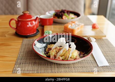 Maki rolls, fried shrimps and tea on table, Japanese cuisine restaurant Stock Photo