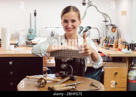 Portrait of a goldsmith in her workshop standing amidst tools