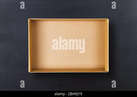 Open cardboard box on chalkboard background. Empty cardboard package on black texture Stock Photo