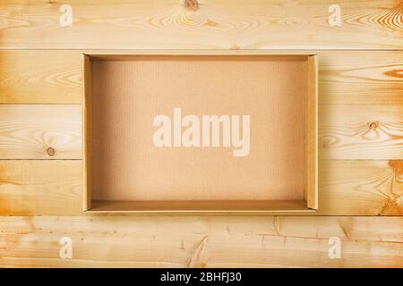 Open cardboard box on wooden background. Empty cardboard package on natural wooden texture Stock Photo