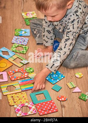 Kid's hands with Montesori pazzls close-up. Montesori wooden game for the development of children. Child development retardation. Stock Photo