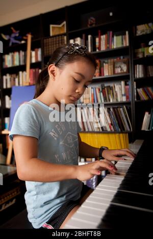 Austin Texas USA, 2012: 10-year-old Japanese-American girl practices playing the piano at home. ©Marjorie Kamys Cotera/Daemmrich Photography Stock Photo