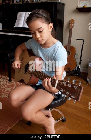 Austin Texas USA, 2012: 10-year-old Japanese-American girl practices playing the guitar at home. ©Marjorie Kamys Cotera/Daemmrich Photography Stock Photo