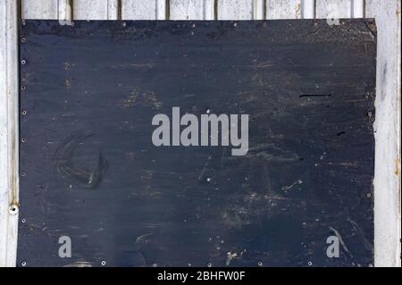 a sheet of black iron with traces of dirt lies on a white profile Stock Photo