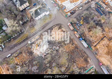 heavy construction machines clearing out pile of debris of destroyed building after demolition. aerial view from flying drone Stock Photo