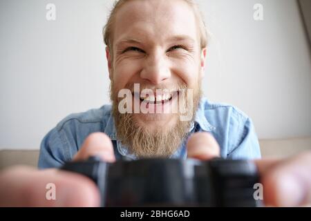 Funny happy young gamer holding joystick playing video game. Closeup. Stock Photo