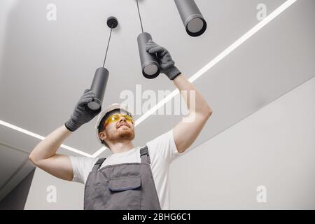 Electrician worker installation electric lamps light inside apartment. Construction decoration concept Stock Photo