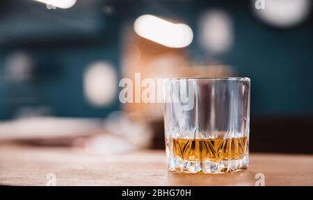 Glass with edges of yellow brown whiskey stands on bar counter in barbershop Stock Photo