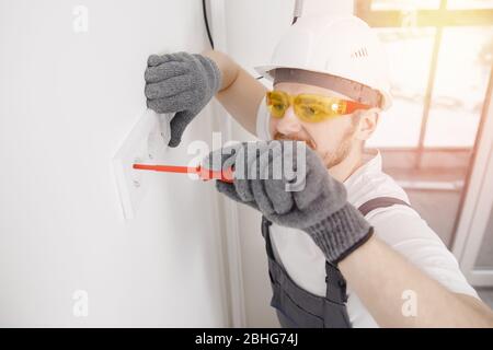 Electrician builder install switches and sockets screwdriver tool working Stock Photo