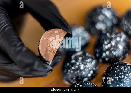 Confectioner holds Belgian chocolate candy, filling of sweets is shown Stock Photo