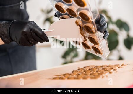 Chef or chocolatier Shakes chocolate molds for sweets Stock Photo