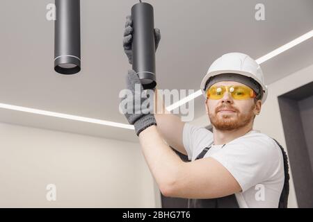 Electrician is repairing lighting fixtures for lamp and spot loft style on ceiling Stock Photo