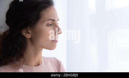 Thoughtful young woman looking away through window. Stock Photo