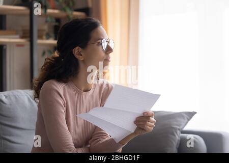 Thoughtful young attractive woman in glasses planning payout. Stock Photo