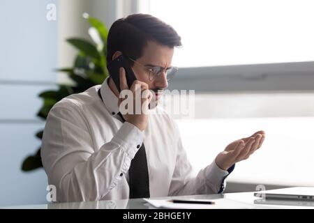 Frustrated businessman angry over bad news message talking on smartphone. Stock Photo