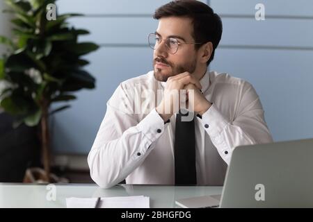 Thoughtful businessman using laptop, pondering online project. Stock Photo