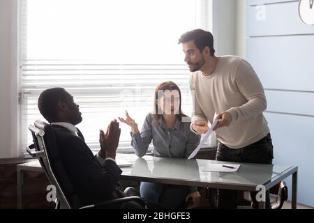 Angry man pointing an error in document to employee. Stock Photo