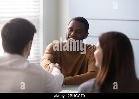 Smiling african american candidate shaking hands with businessman recruiter. Stock Photo