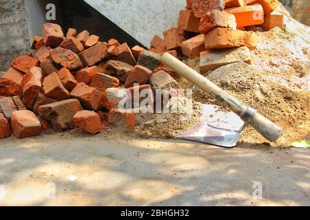 Stack of red clay Bricks and sand Shovel on filed construction site. Stock Photo