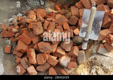 Stack of red clay Bricks and sand Shovel on filed construction site. Stock Photo
