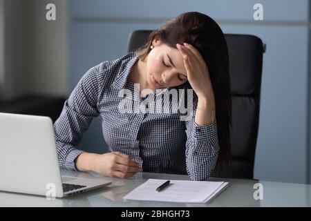Unhappy attractive businesswoman suffering from headache at work at laptop. Stock Photo