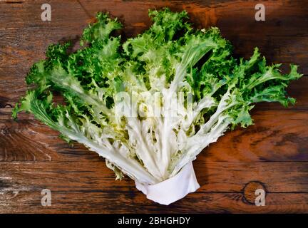 Green leafy endive on wooden table ,beautiful curly endive with outside green leaves and white inner leaves Stock Photo