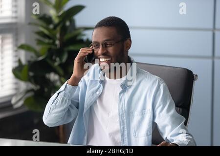 Happy african american businessman wearing glasses talking on phone. Stock Photo