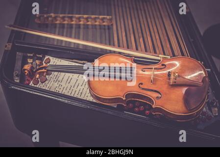 Antique violin and violin bow lying on dulcimer. Close up a violin instrument and cymbal Stock Photo