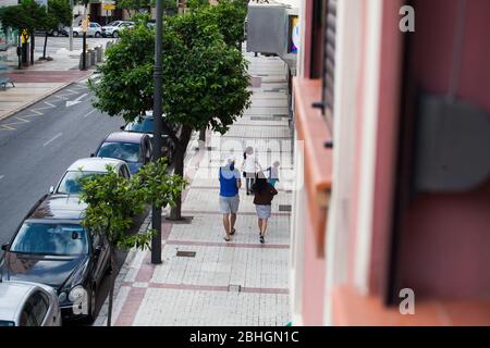 A family walks down the street in Malaga, Spain. Children in Spain are finally allowed to go outside for a walk for the first time since the Coronavirus lockdown began in March. Stock Photo